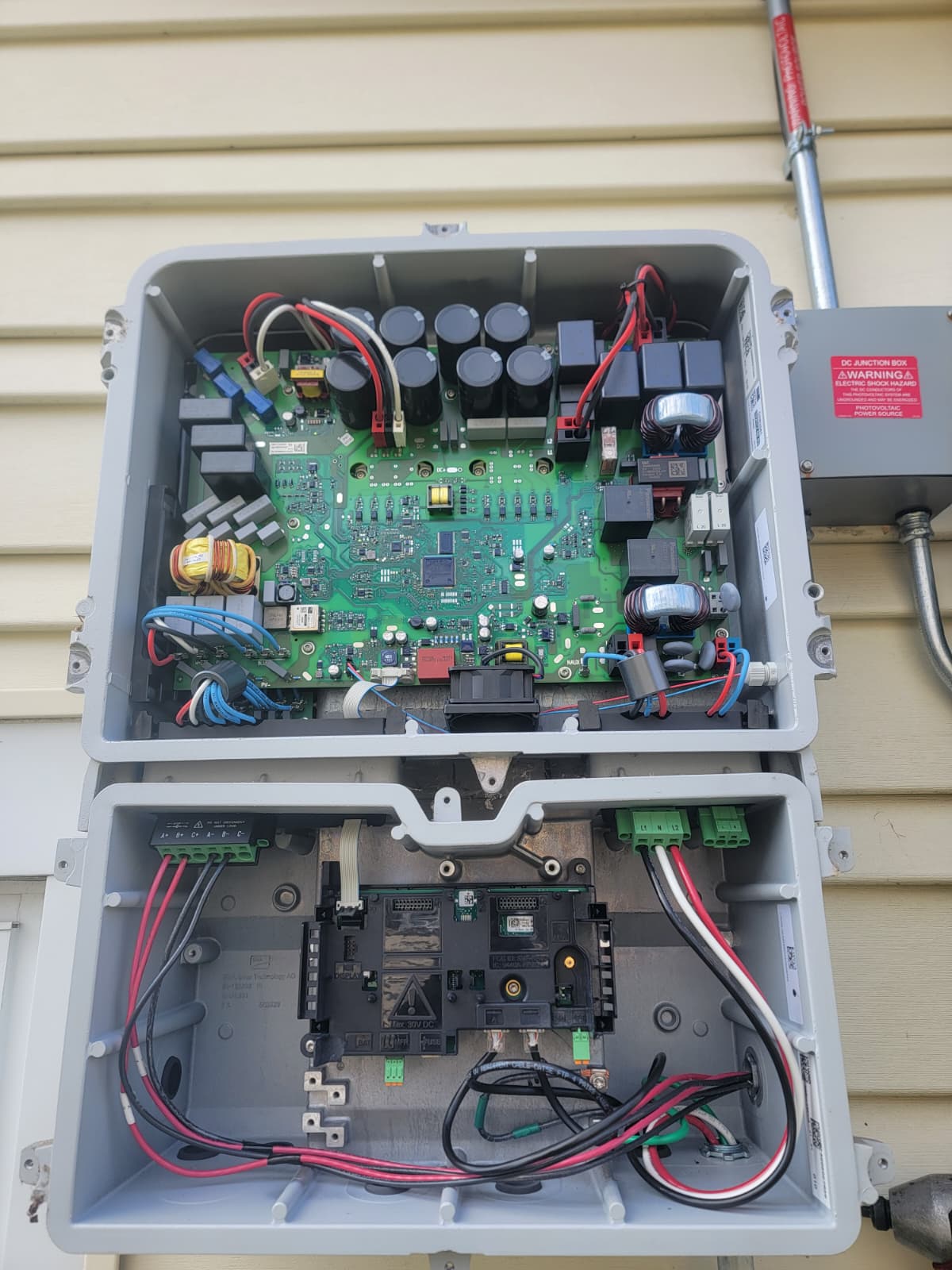 SMA Sunny Boy inverter opened for service beside the DC junction box on a home exterior