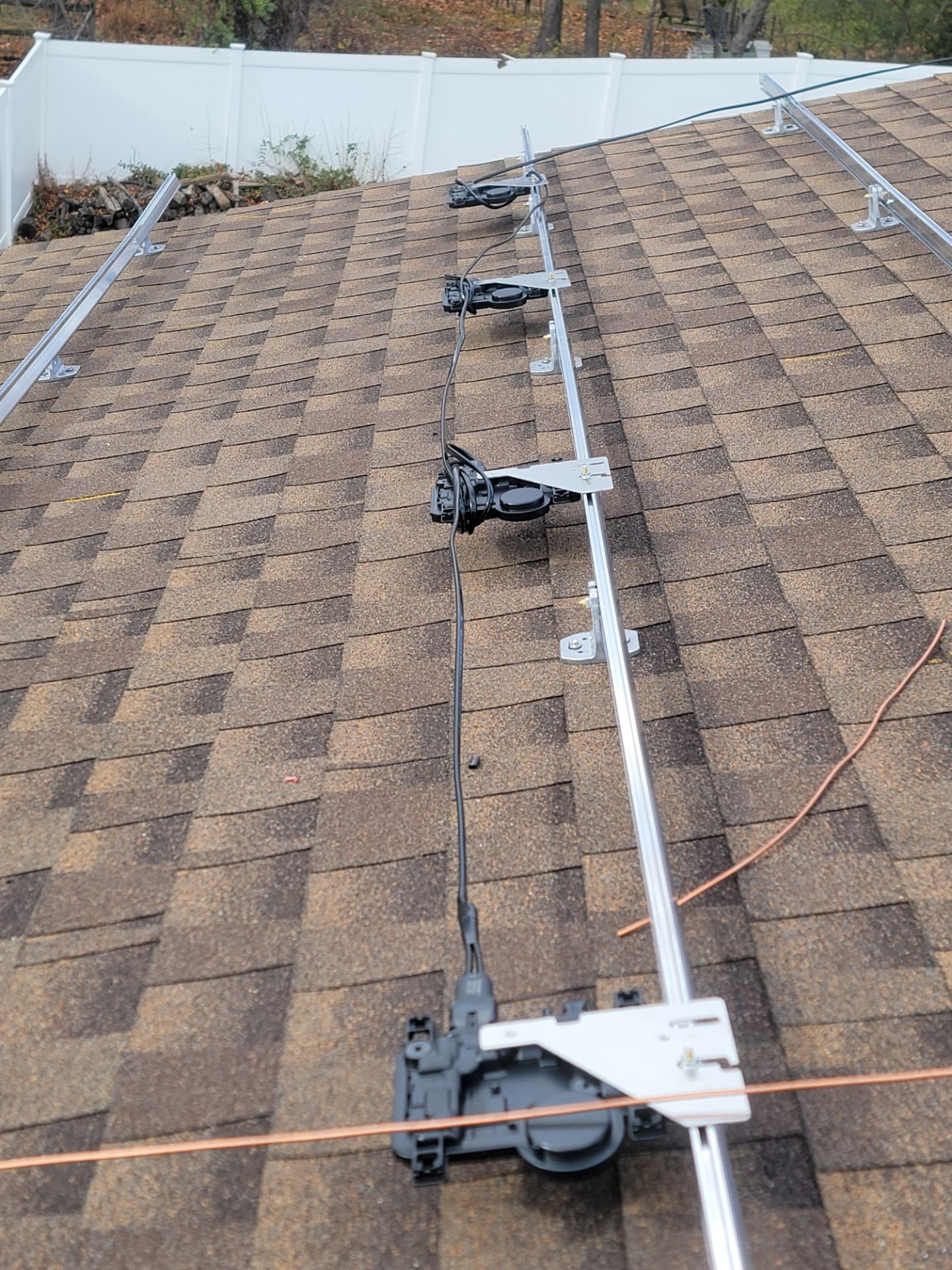 Enphase microinverters mounted along a roof rail with trunk cabling