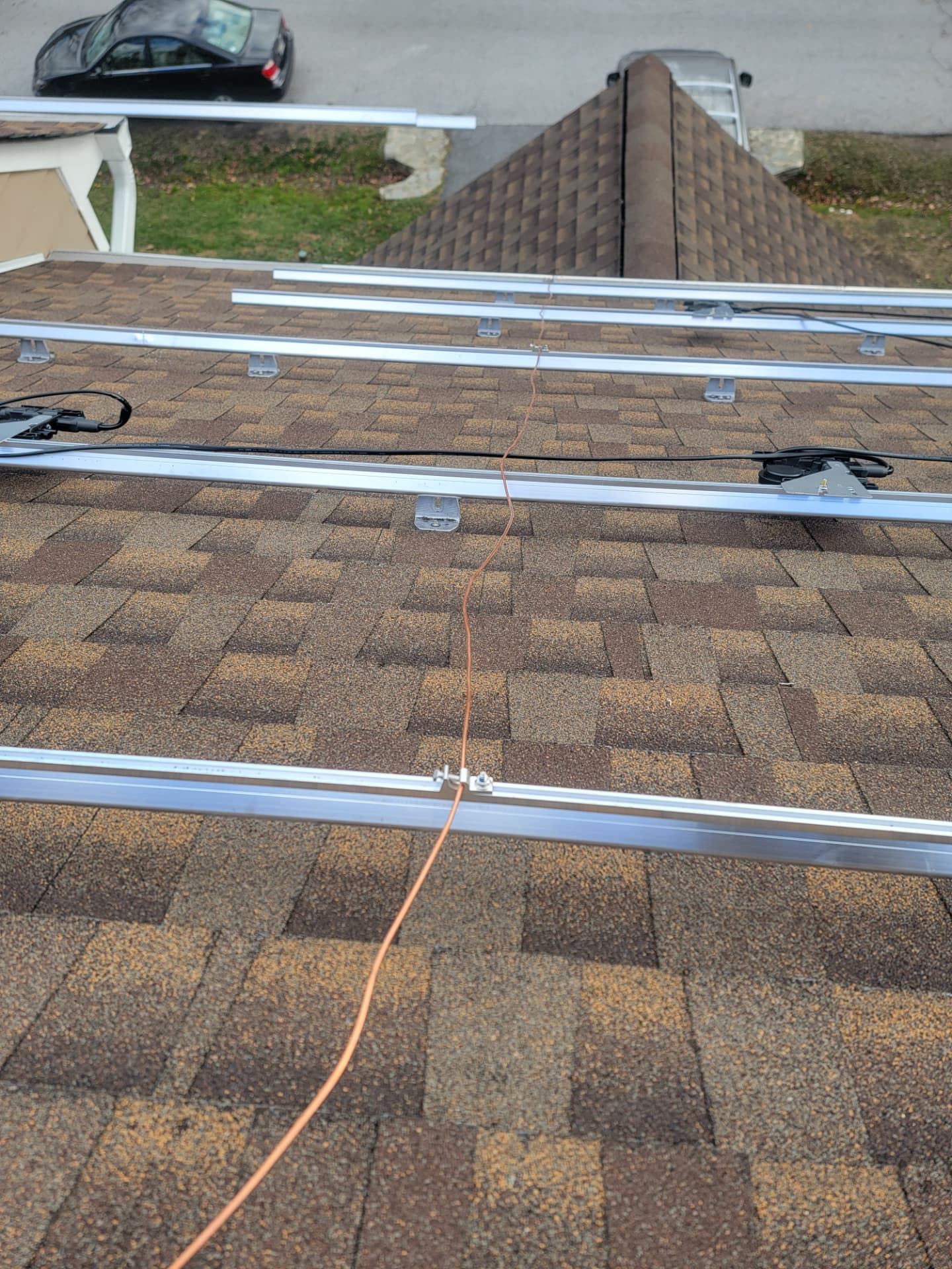 Aluminum solar mounting rails with copper grounding conductor on a shingle roof
